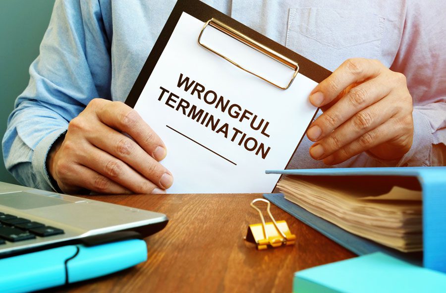 attorney holding a clipboard with a paper that says "wrongful termination"